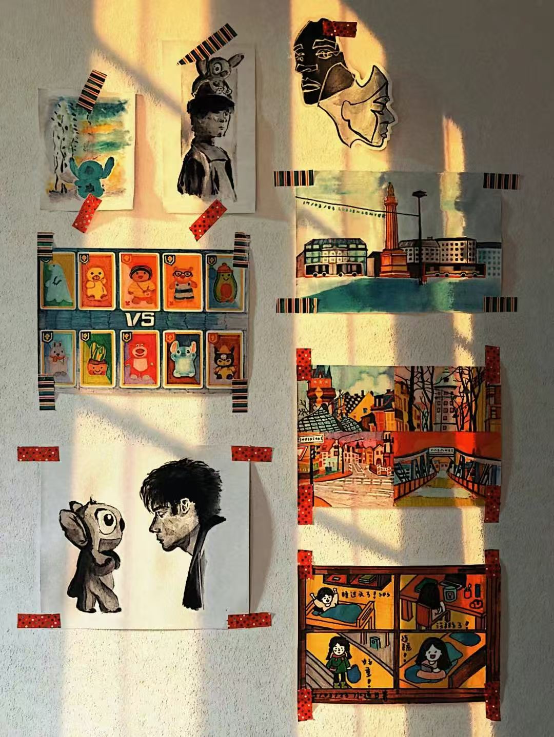 A sunlit wall displaying drawings and mixed-media artwork